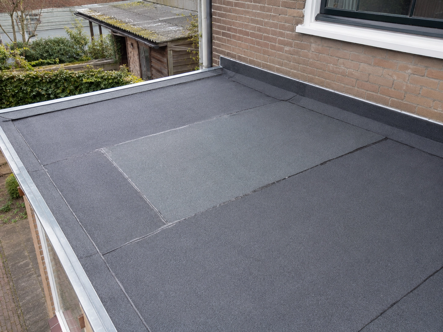 Afgewerkt plat dak met vernieuwde dakbanen en dakrand